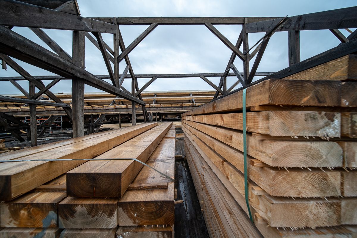 Sawn timber planks stacked under a storage structure at a commercial lumber facility